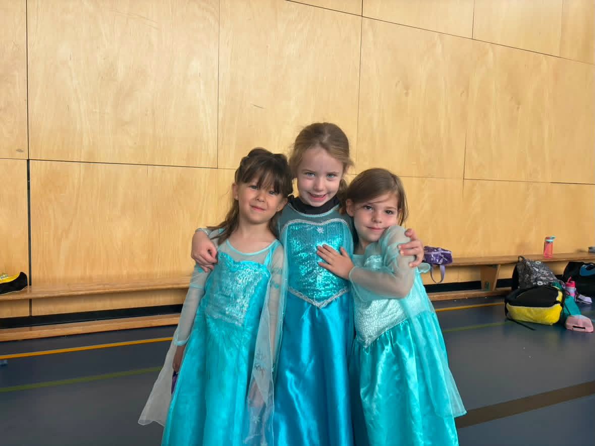 Young campers dressed in princess costumes during indoor bilingual camp play