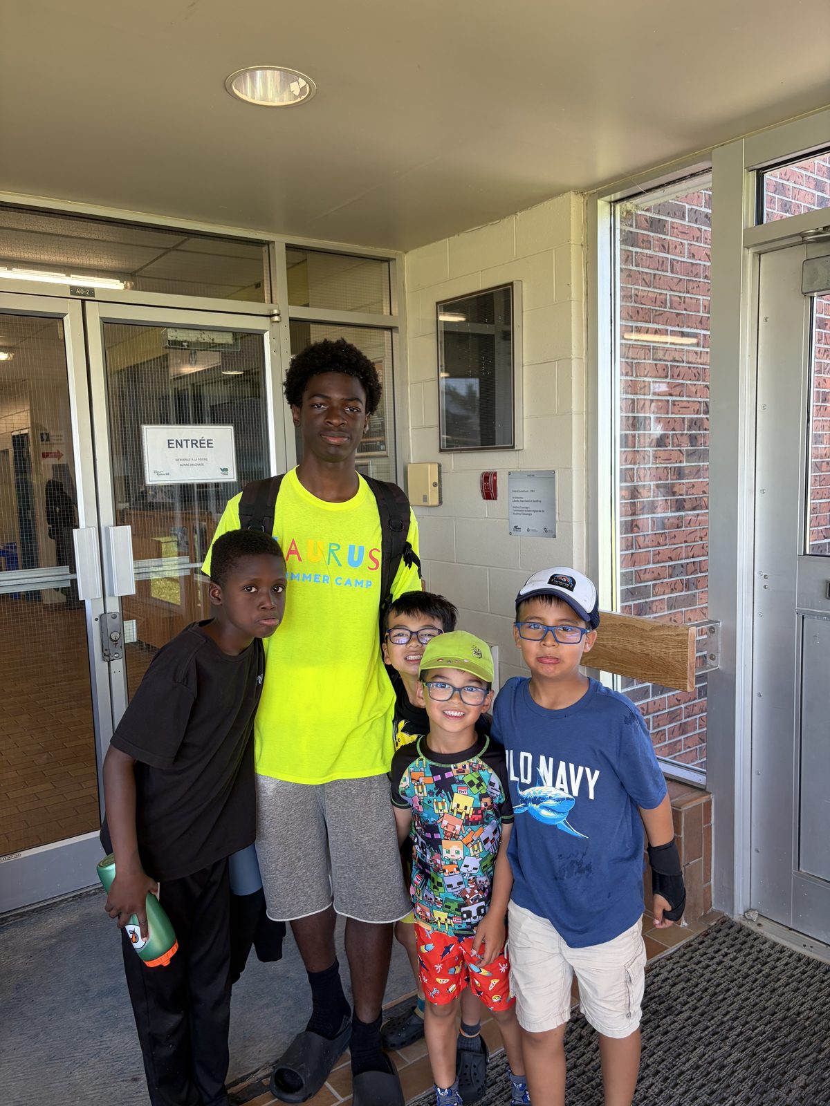 Campers and a counselor posing together in a school hallway at Laurus Summer Camp in Ottawa
