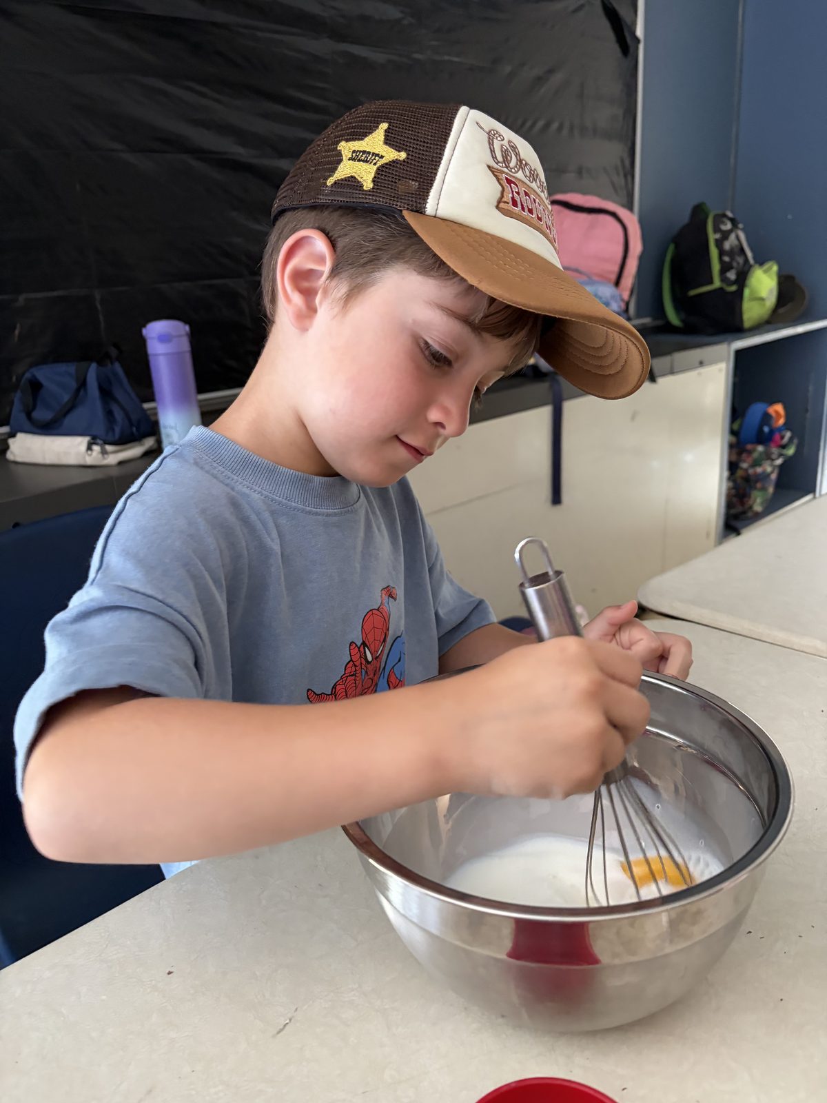 Campeur mélangeant des ingrédients lors d'une activité culinaire pratique au camp d'été bilingue Laurus