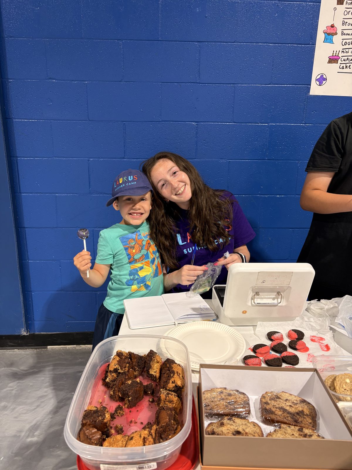 Counselor helping a young camper during a hands-on table activity at Laurus summer camp