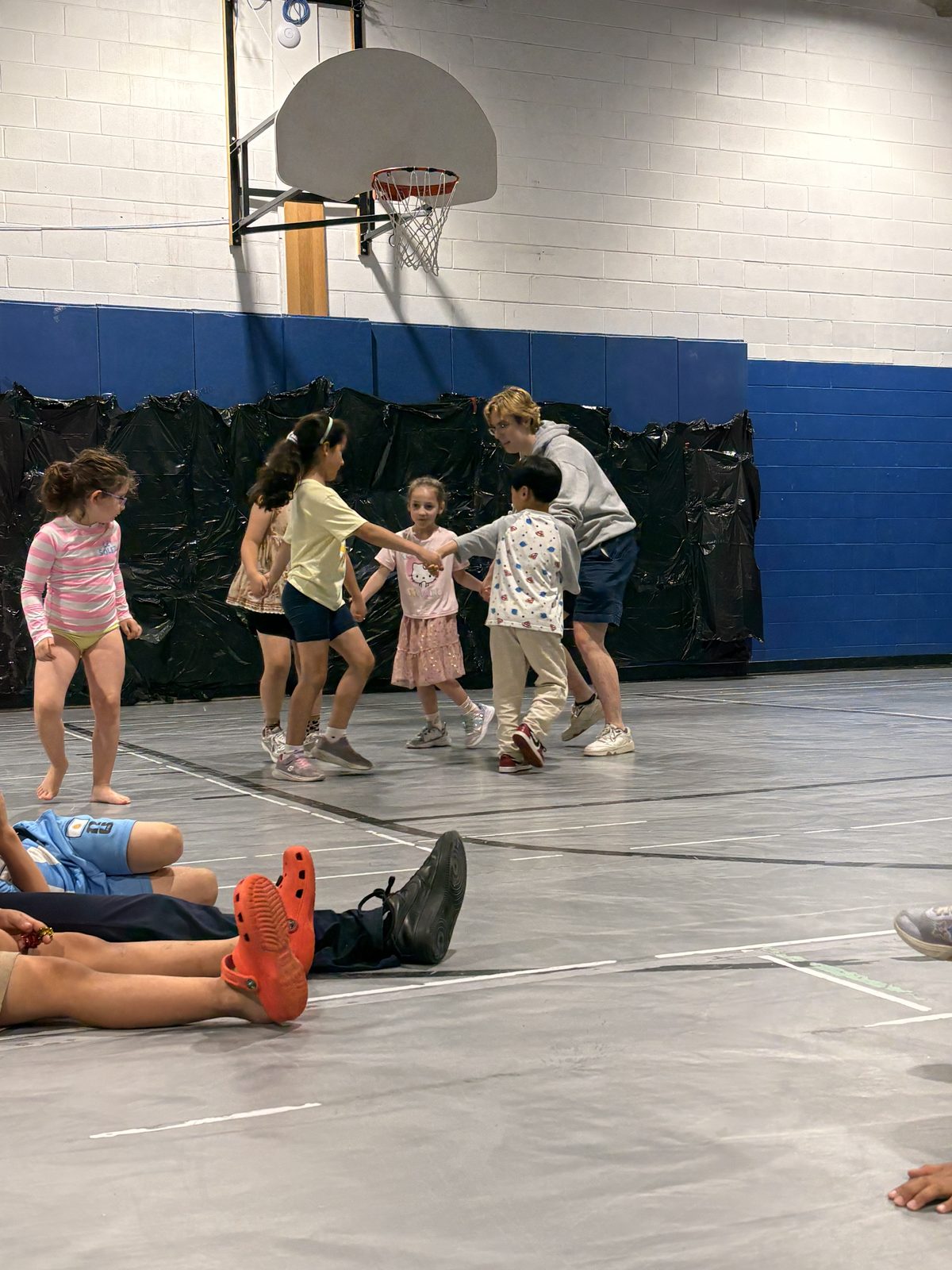 Campers playing an active group game in the gym under counselor supervision