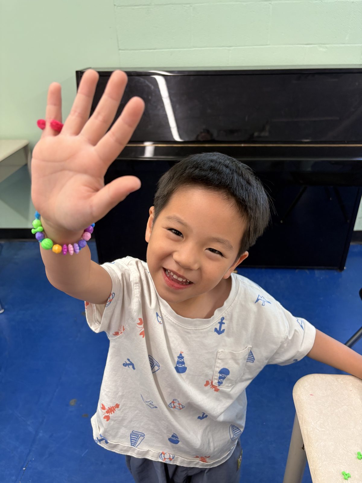 Smiling young camper waving outdoors during bilingual summer camp